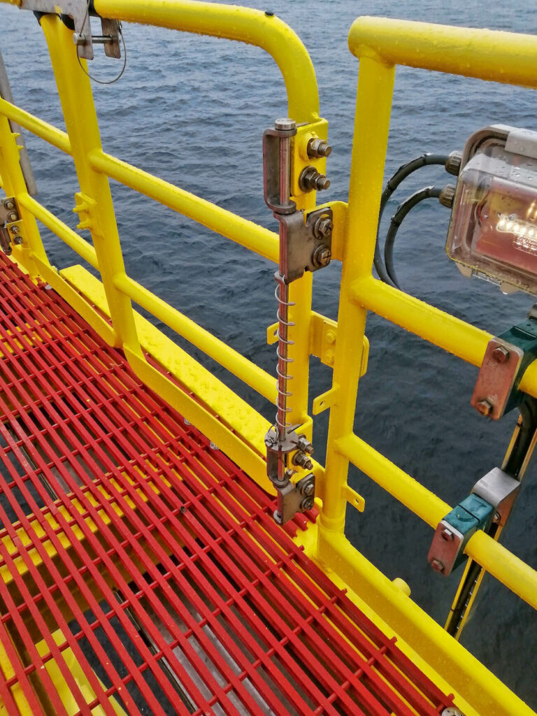safety gate hardware shown on an access gate on offshore wind farm. Yellow gate on red grating.