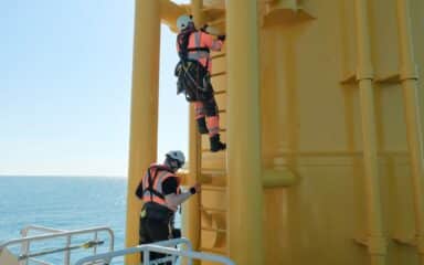Workers climbing an access ladder on an offshore platform