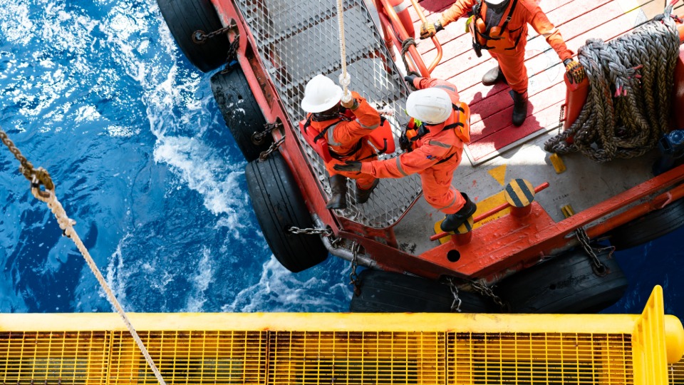 workers moving from offshore platform to transfer boat